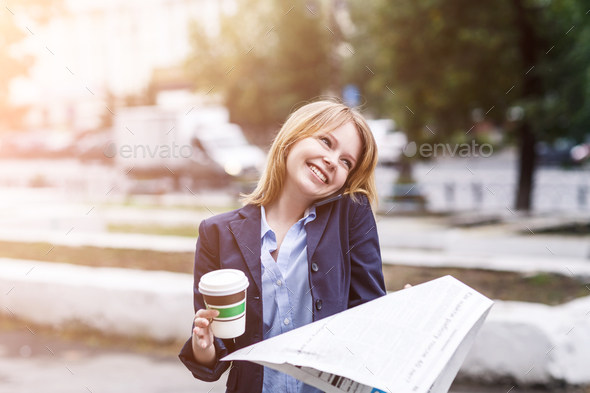 Portrait of business woman with to go coffee and newspaper in hands