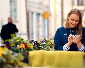 Woman Using Her Smartphone Sitting In Outdoor Cafe